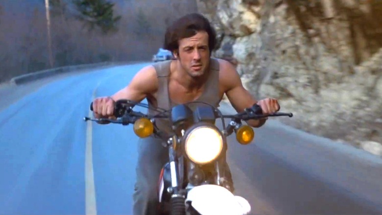 Sylvester Stallone as Rambo on a stolen bike in a "First Blood" chase scene.