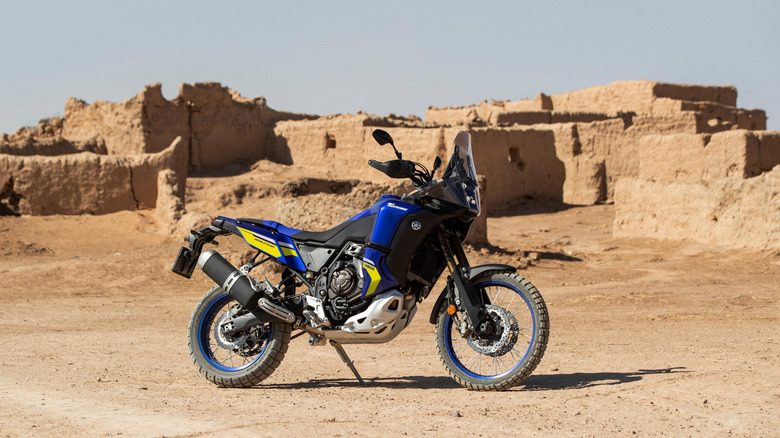 A side shot of the Yamaha Tenere 700 World Raid parked in front of an old desert building.