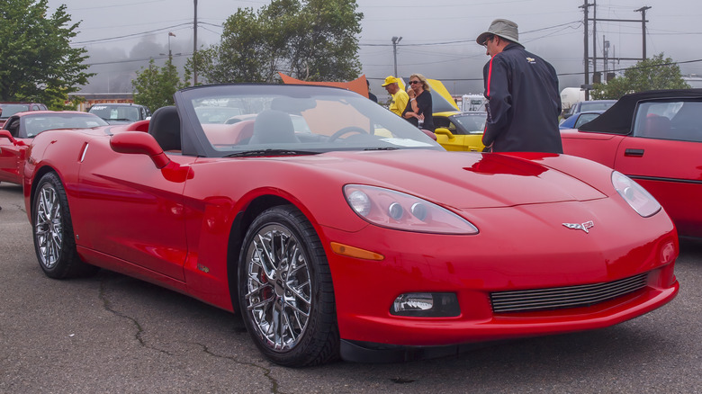 Person beside red C6 Corvette