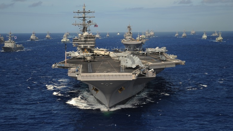 Nimitz-class aircraft carrier out on sea escorted by other vessels