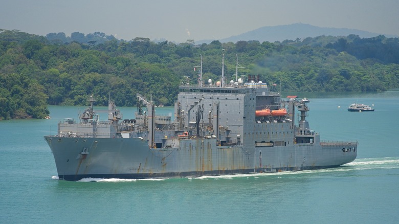 Gray and rusty Lewis and Clark-class cargo/ammuntion ship on the straits