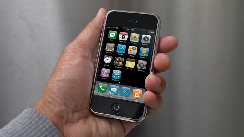 A person holding the first version of the iPhone.