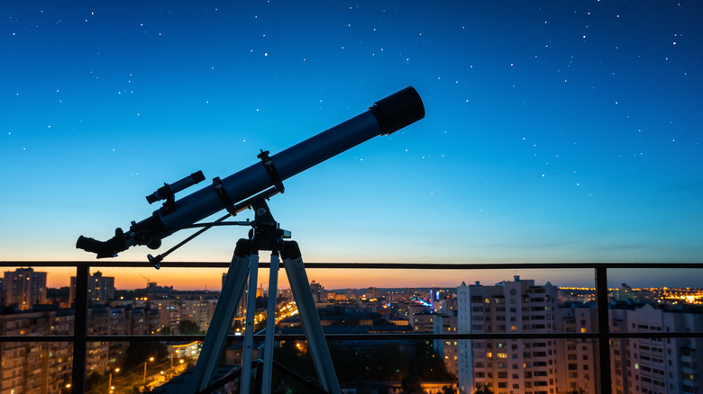 Telescope looking over city sky