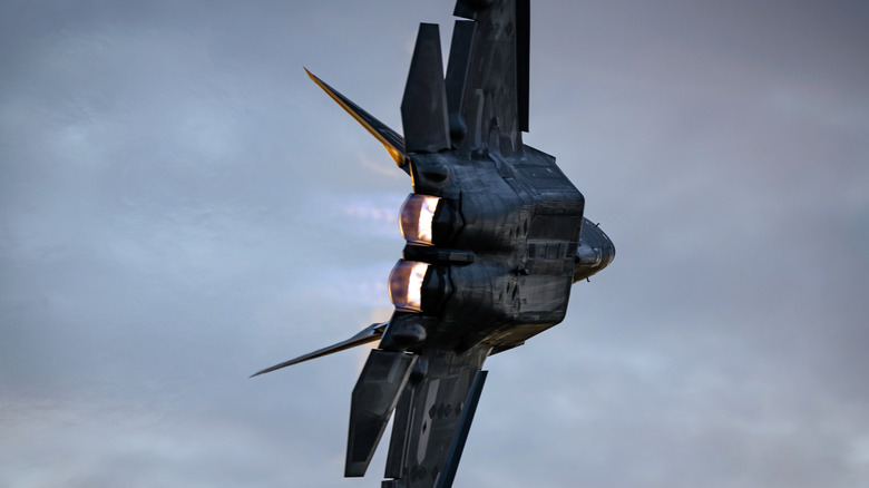 A F-22 Raptor banks into a turn, showcasing its jets on full blast.