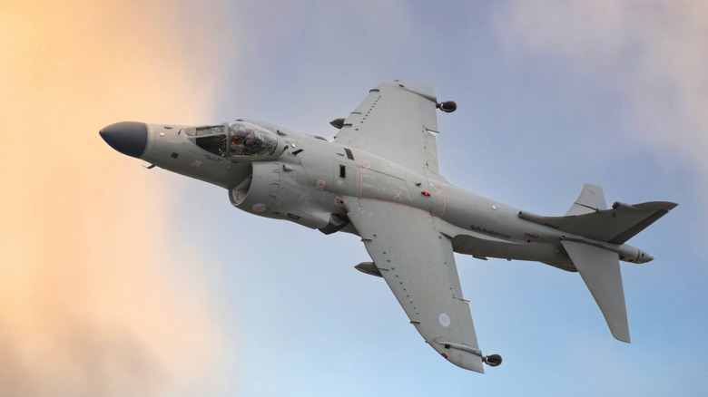 A grey British Harrier Jump Jet turns in the sky at dawn