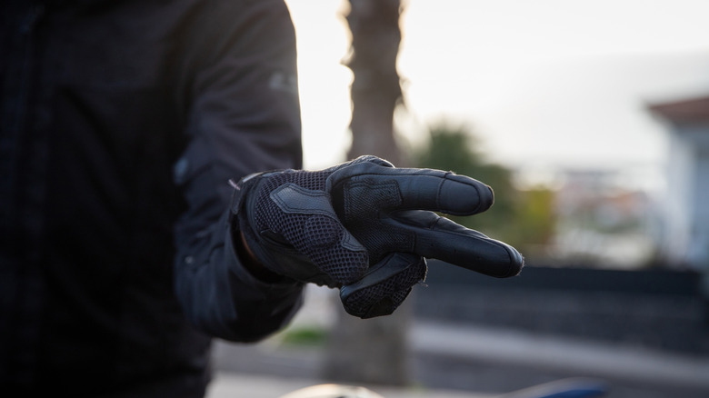 A close-up of a biker wearing gloves showing a V sign
