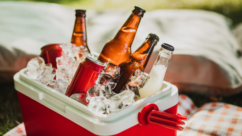 A cooler full of ice and drinks on a picnic blanket