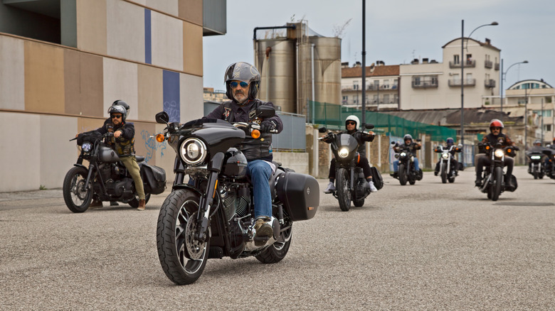 Group of people riding Harley-Davidsons through a city