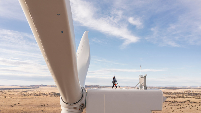 A shot of a worker walking on top of a MW turbine in New Mexico