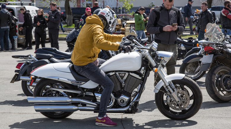 A biker in a white helmet and yellow jacket on a motorcycle Victory Vegas 8-Ball