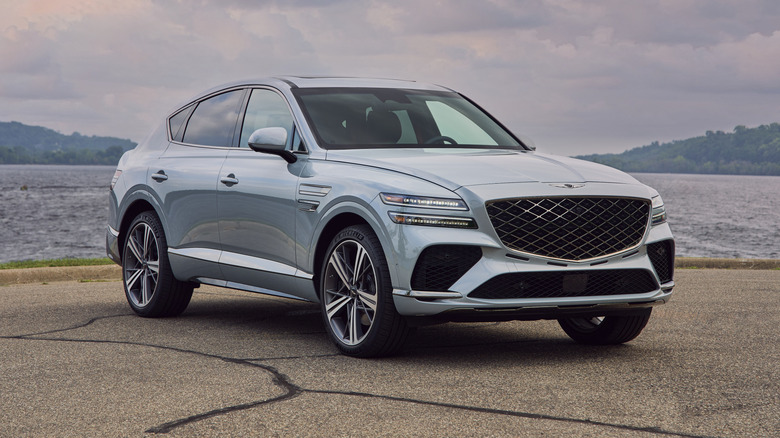 Front 3/4 view of silver Genesis GV80 Coupe by the waterside