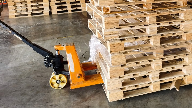 A pallet jack being used to move a stack of unused pallets