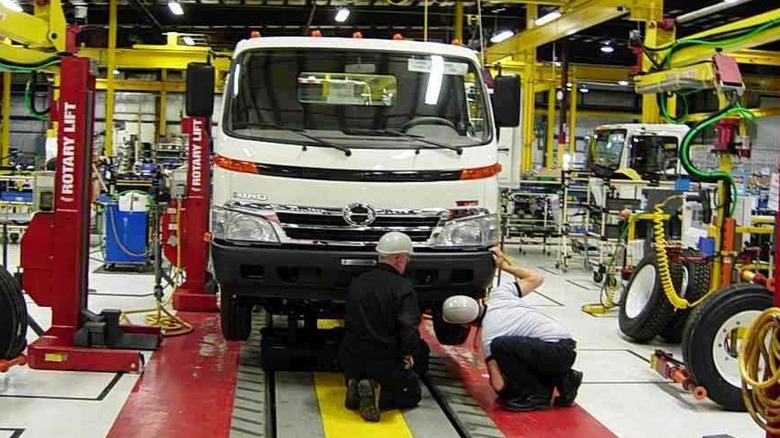 Two workers checking Hino truck in a plant