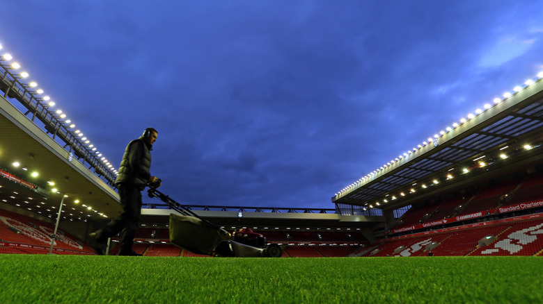 Man cutting stadium field grass at night