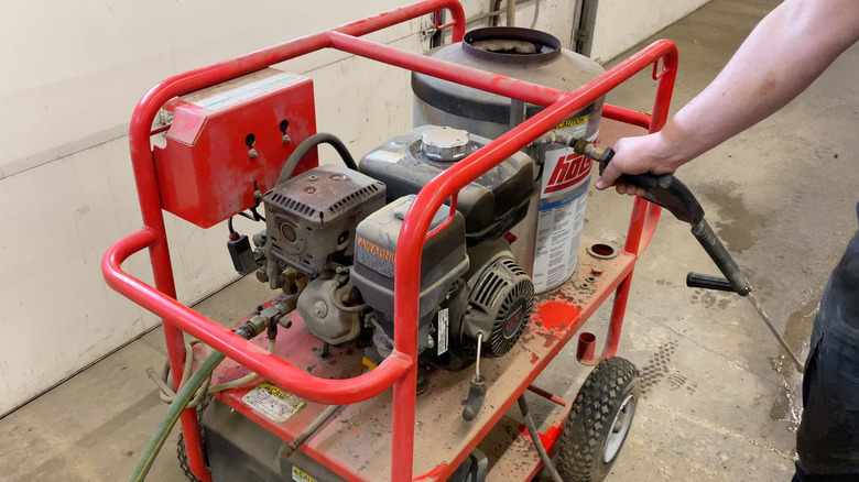 A person demonstrating a Hotsy pressure washer with a gas engine