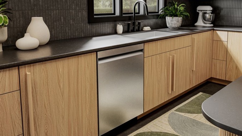 KitchenAid dishwasher installed left of sink in kitchen with wooden drawers