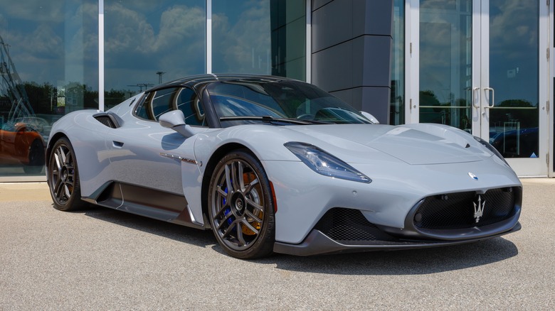 Primer grey Maserati MC20 supercar parked outside a dealership