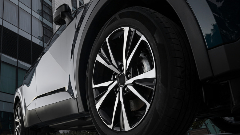 An aluminum rim and black tire on a black sedan