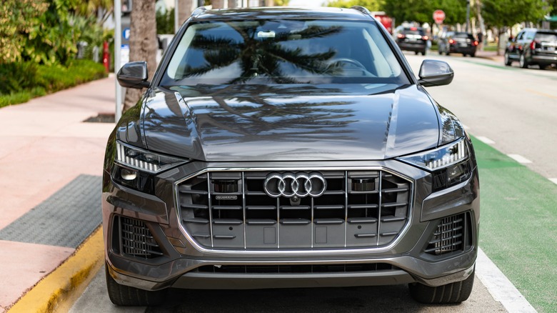 Front end of a parked gray Audi Q8 SUV on city streets.