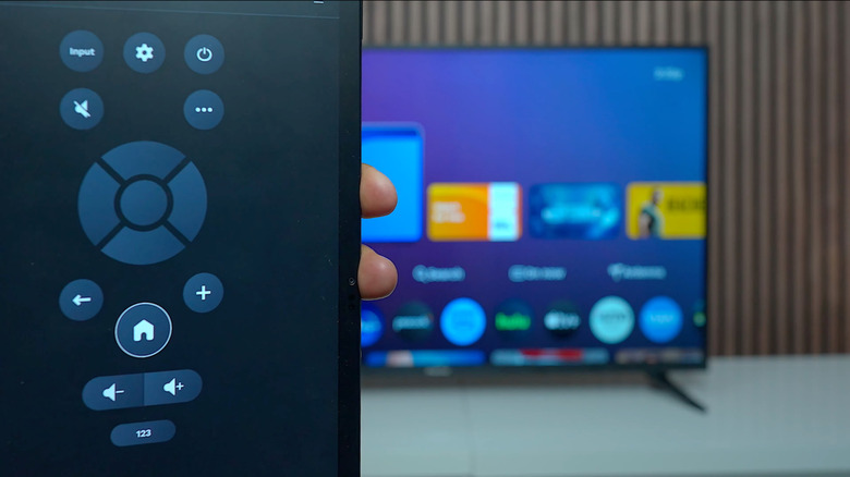 A close-up of a smartphone being used as a Xumo remote, with a Pioneer TV running Xumo in the background