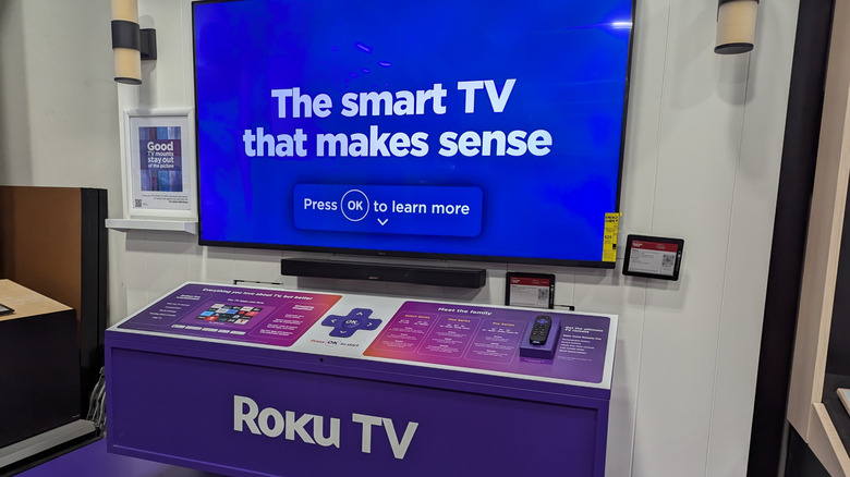 A Roku smart TV displayed at a store complete with promotional materials and a user manual