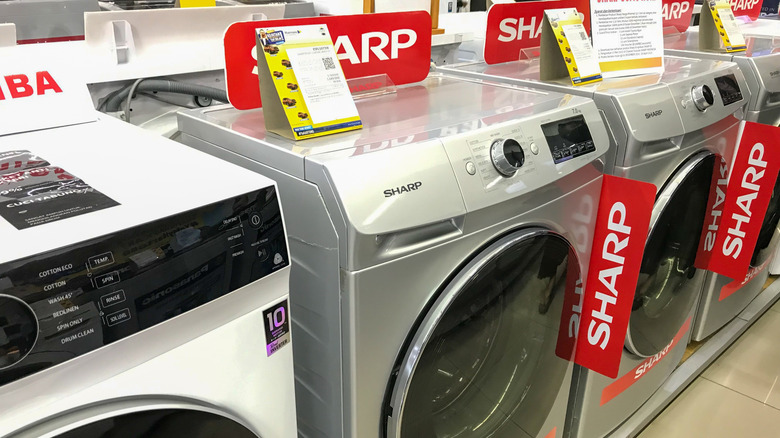 A lineup of Sharp washing machines on display in a retail store