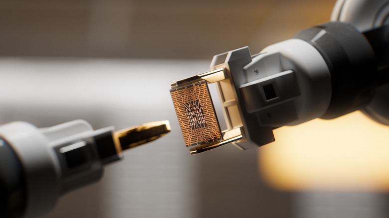 Automated robotic arms handling a microchip inside of a factory.