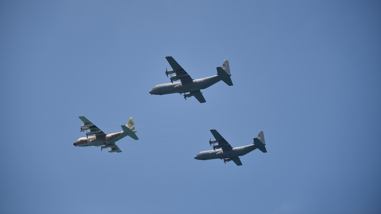 Three C-130s flying in a triangle formation in the sky