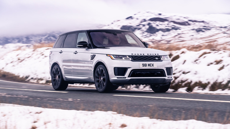 A second generation Range Rover Sport in white, front 3/4 view, countryside in the background