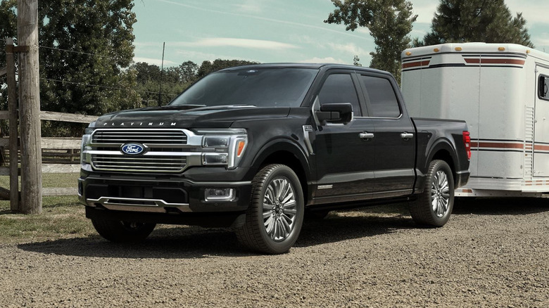 2025 Ford F-150 Powerboost Hybrid truck connected to a trailer, parked outside a horse ranch