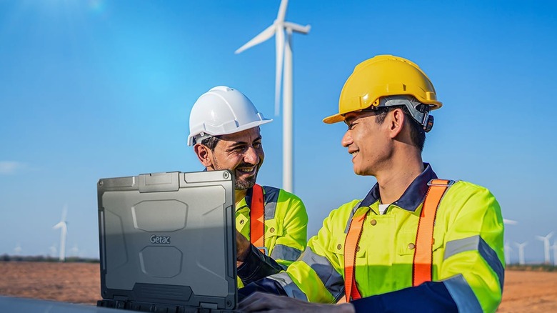 Two people on a wind farm using a Getac tough laptop.