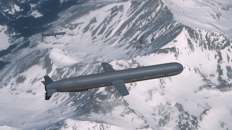 Two Tomahawk cruise missiles flying high above snow covered mountains.