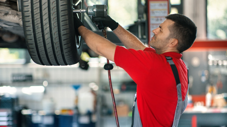 A mechanic in a shop installing tires on a vehicle.
