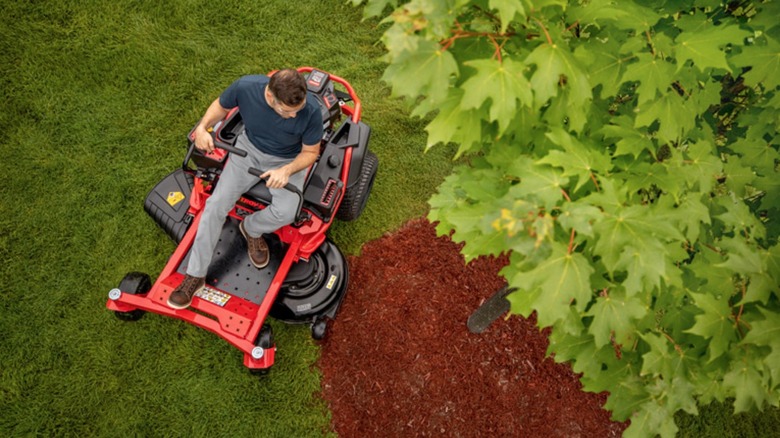 Person mowing lawn with at Troy-Bilt riding mower