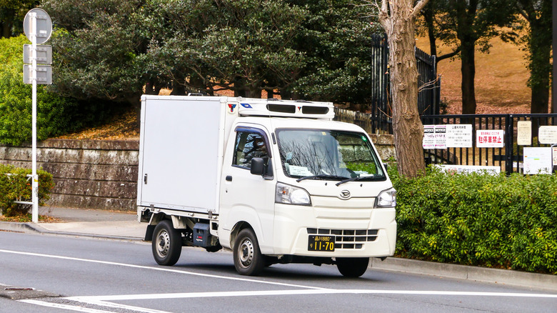White Daihatsu HiJet refrigerator truck on an urban road