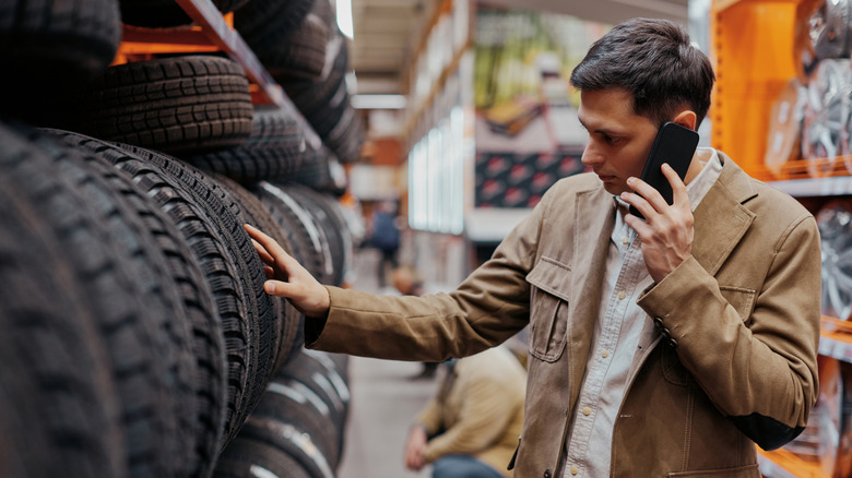 Person talking on a mobile phone while looking at car tires