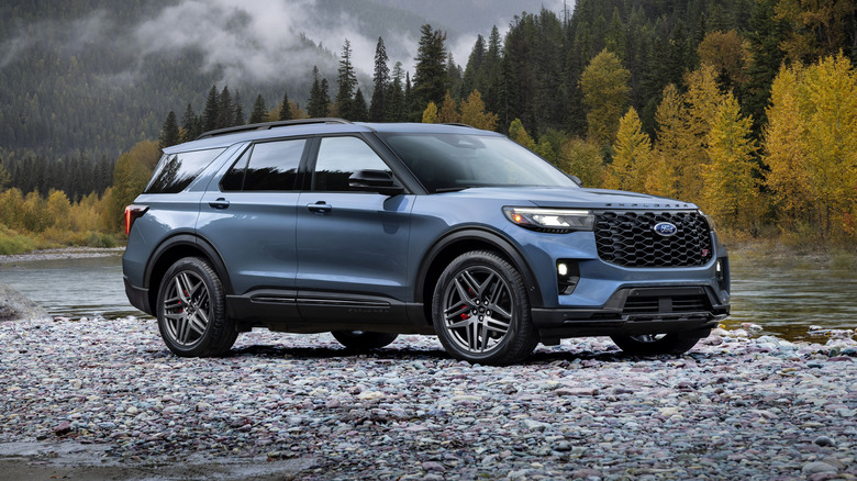 Ford Explorer ST parked on a riverbank with mountains and forests in the background