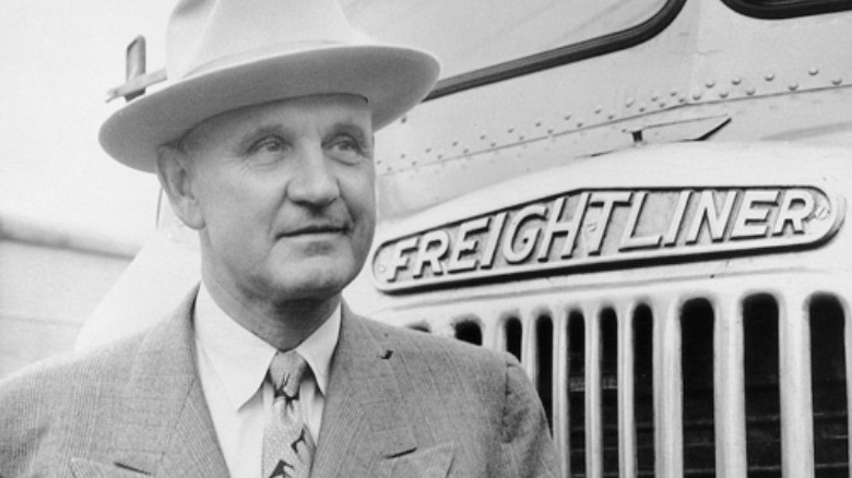 Founder Leland James posing in front of truck with Freightliner nameplate