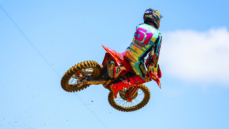 A biker on a GasGas off-road bike takes off into the air against a blue sky