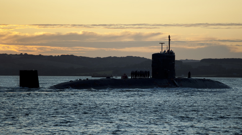 Side view of a mostly submerged submarine at sunset