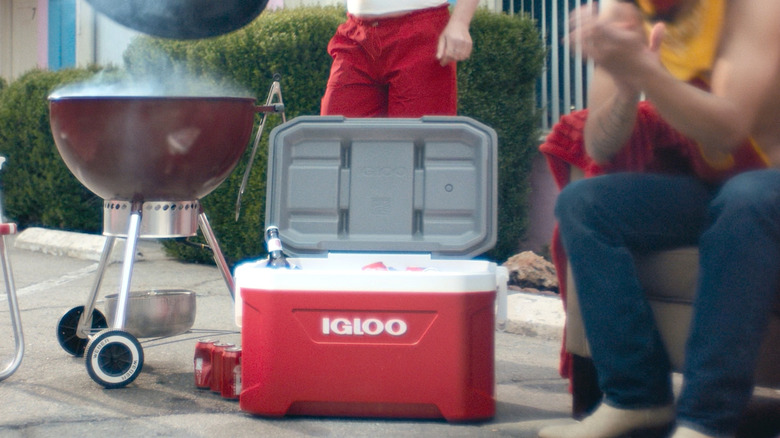 Igloo cooler cooling drinks by a hot grill