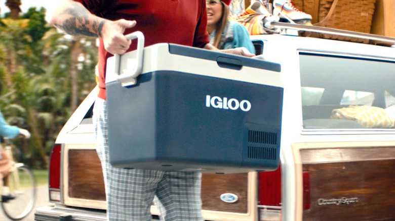 Person carrying an Igloo cooler.