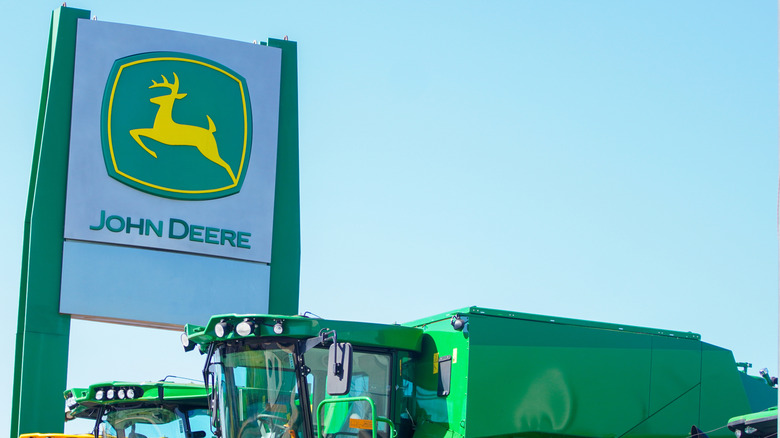 a John Deere dealership signage next to several green heavy machinery