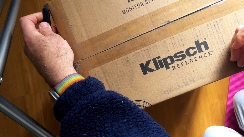 A close-up of a person's hands holding a box that's labeled Klipsch Reference