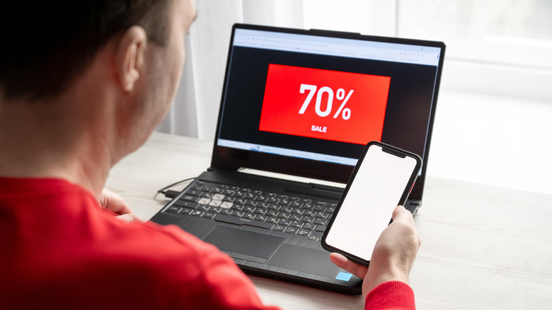 A man is looking for a bargain on a laptop and smartphone with discounts