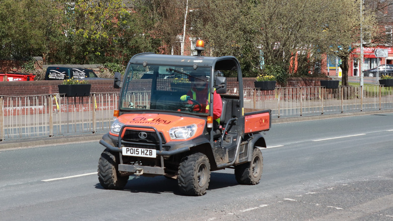 A Kubota RTV owned by the Chorley Council in the UK driving on the road, front 3/4 view