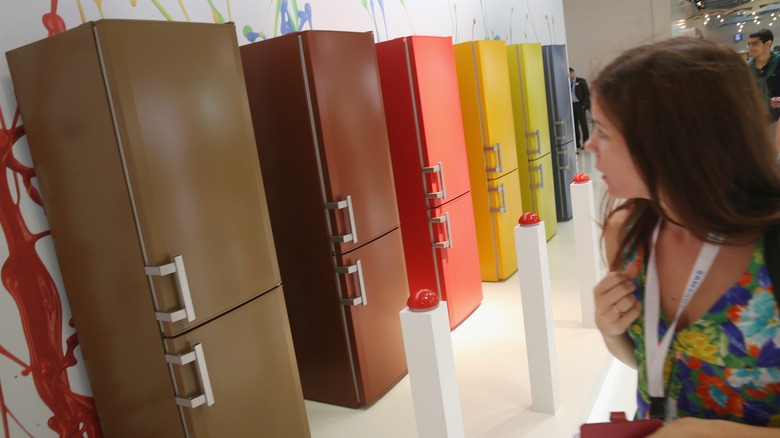 A person viewing different colored Liebherr refrigerators on display in a row at the IFA trade show