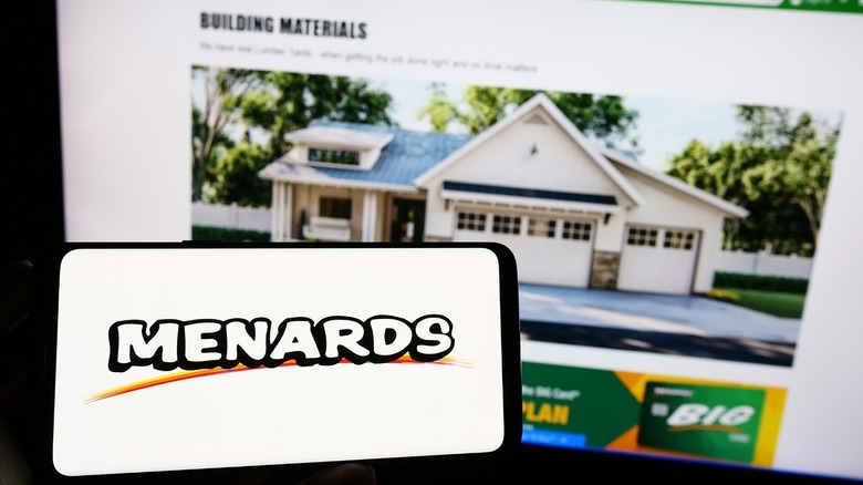 A cellphone showing the Menards logo with the Menards website in the background