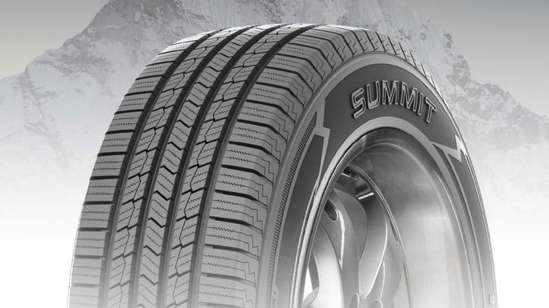 A Summit-branded tire displayed against a backdrop showing the top of a mountain