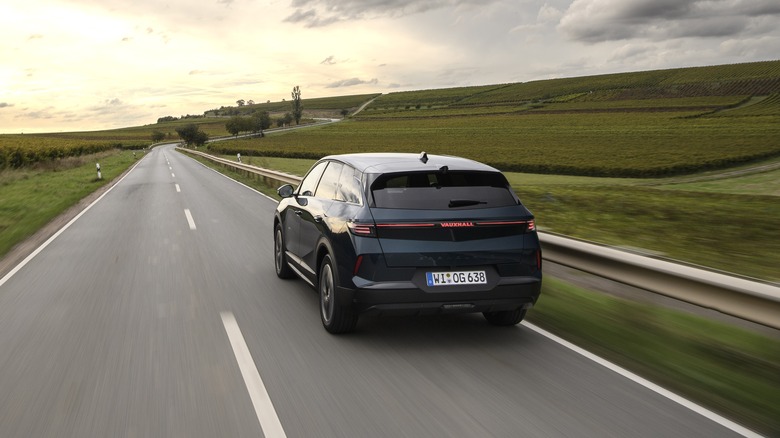 A new Opel Grandland Hybrid on the move on an open road, rear 3/4 view